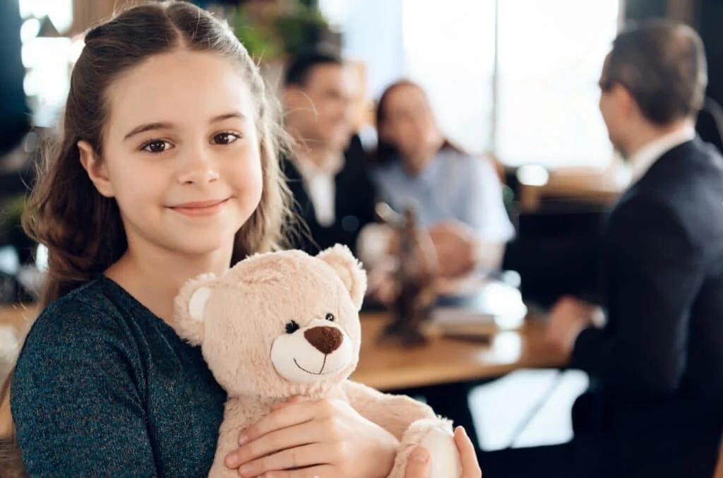 stock photo happy little girl is hugging teddy bear at office of family lawyer registration of guardianship 1055292173 transformed 1024x677 1